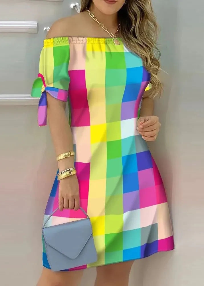 Woman wearing a colorful checkered dress holding a blue handbag against a neutral background