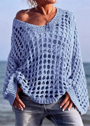 Person wearing a light blue crochet sweater by the ocean