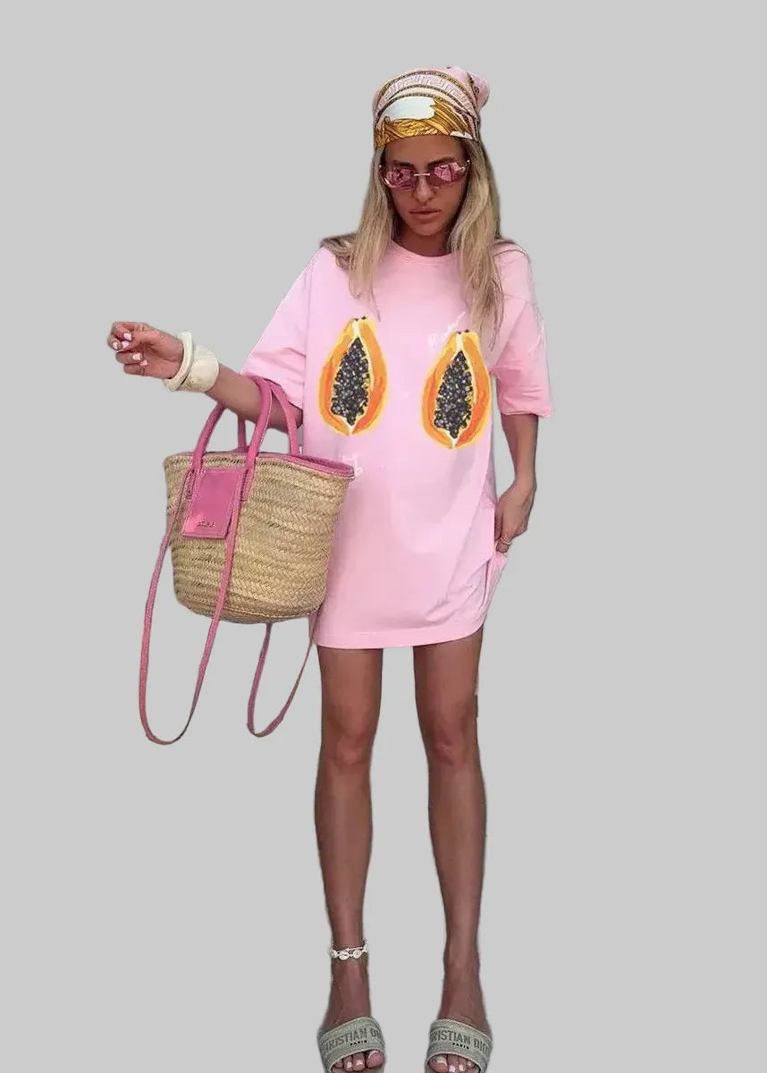 Woman wearing a pink dress with papaya design outdoors