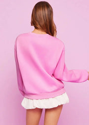 Person wearing a pink sweatshirt and white skirt against a pink background