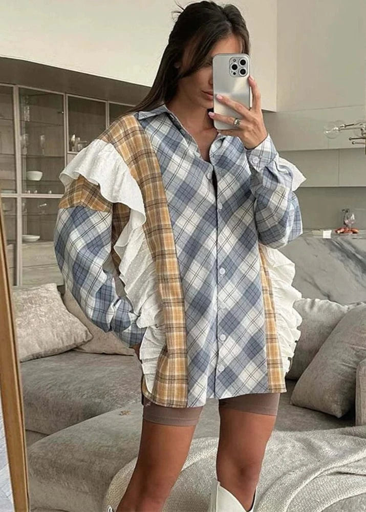 Person wearing a plaid shirt with ruffled sleeves in a living room.