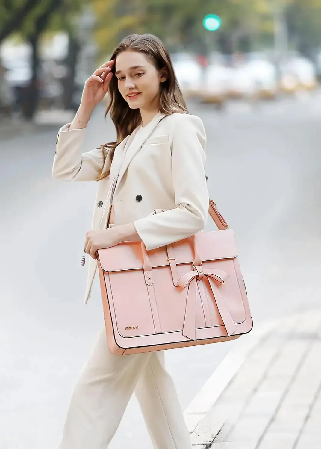 Woman holding a pink and brown handbag on a city street