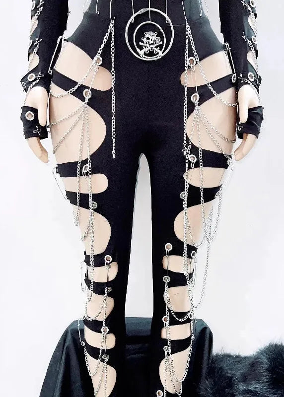 Black strappy cutout bodysuit with silver chain drapes, matching fingerless gloves, and a skull-and-crossbones pendant, shown on a mannequin against a white background.