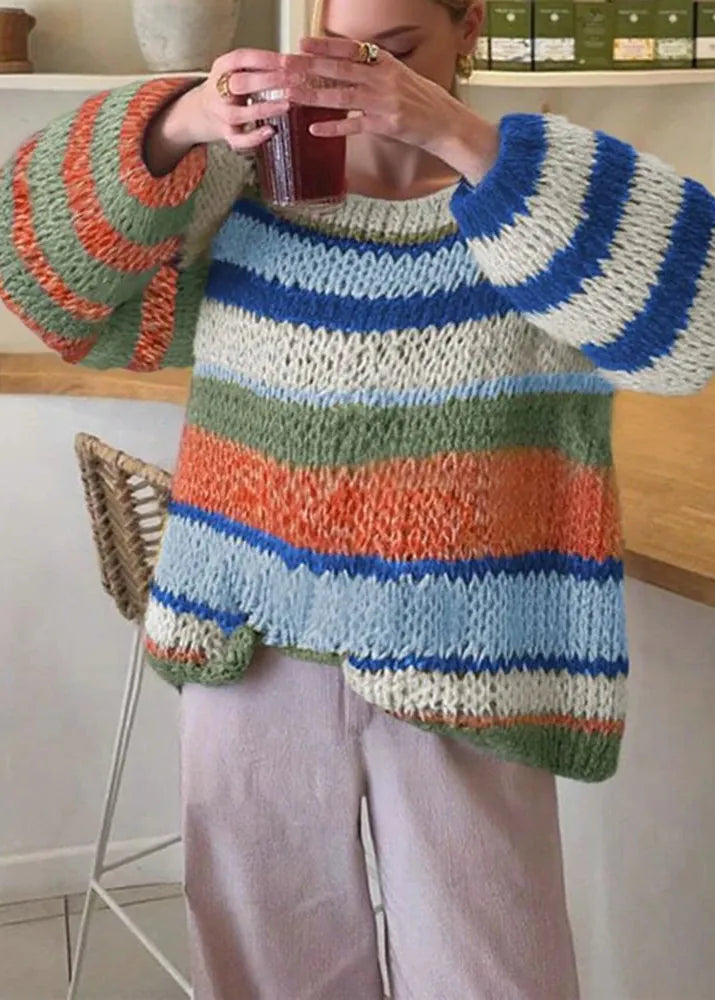 Person wearing a colorful striped sweater holding a glass.
