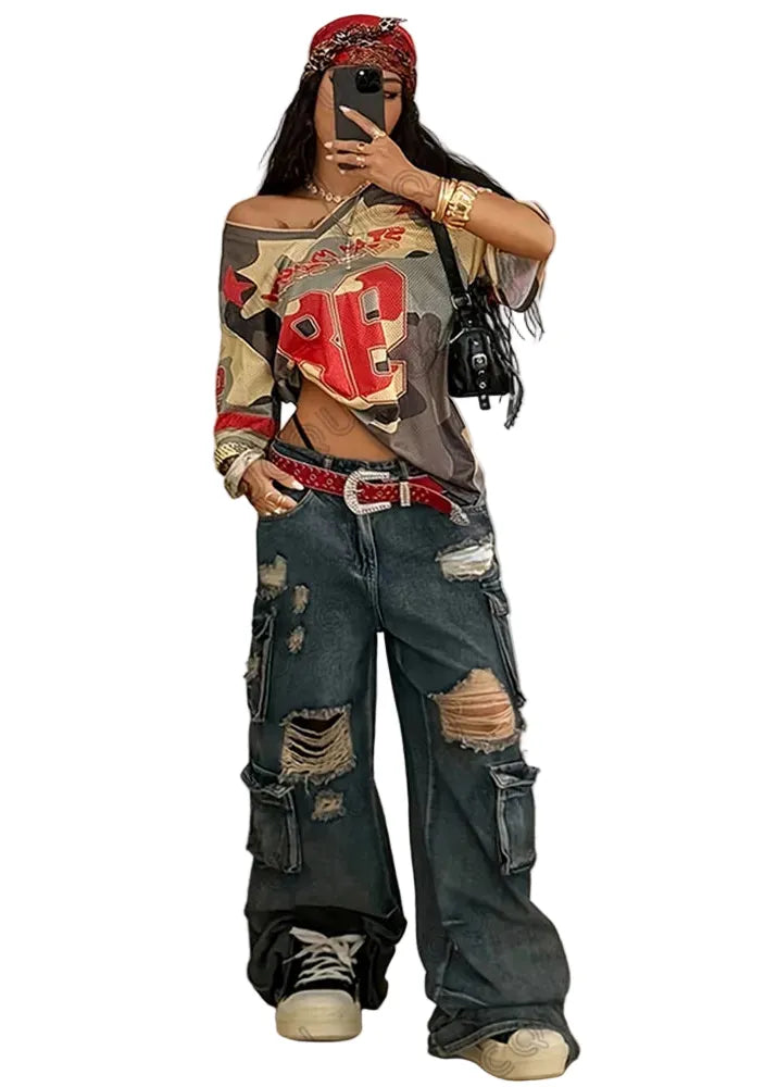 Person wearing a camouflage jacket with red lettering and ripped jeans, taking a mirror selfie.
