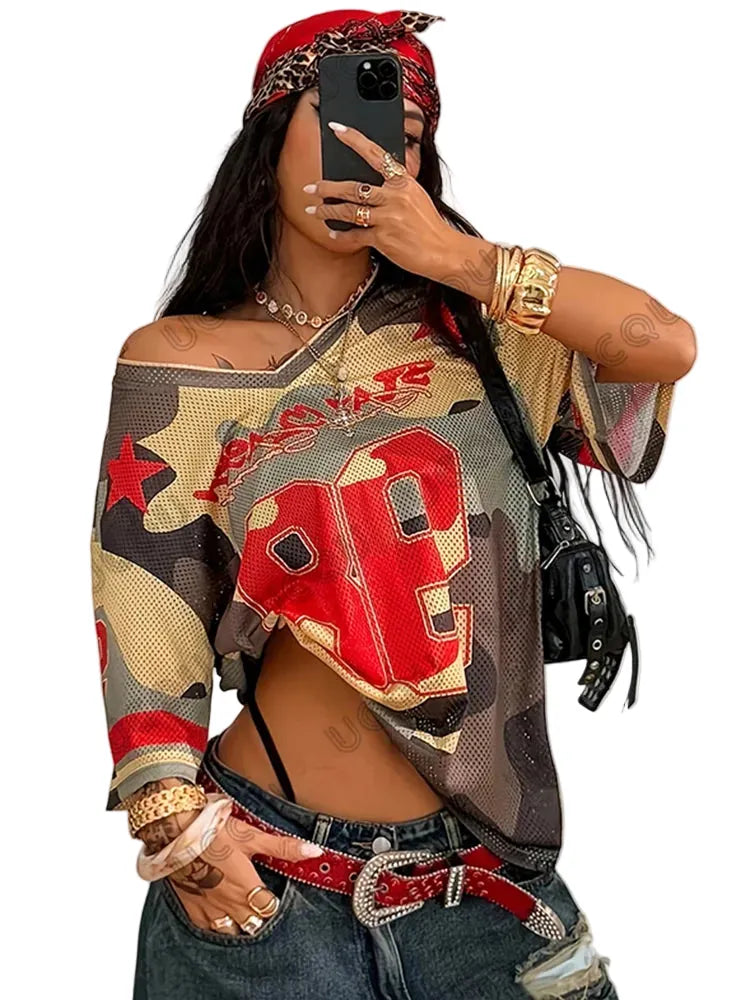 Person wearing a colorful off-shoulder top with red and beige patterns, taking a mirror selfie.