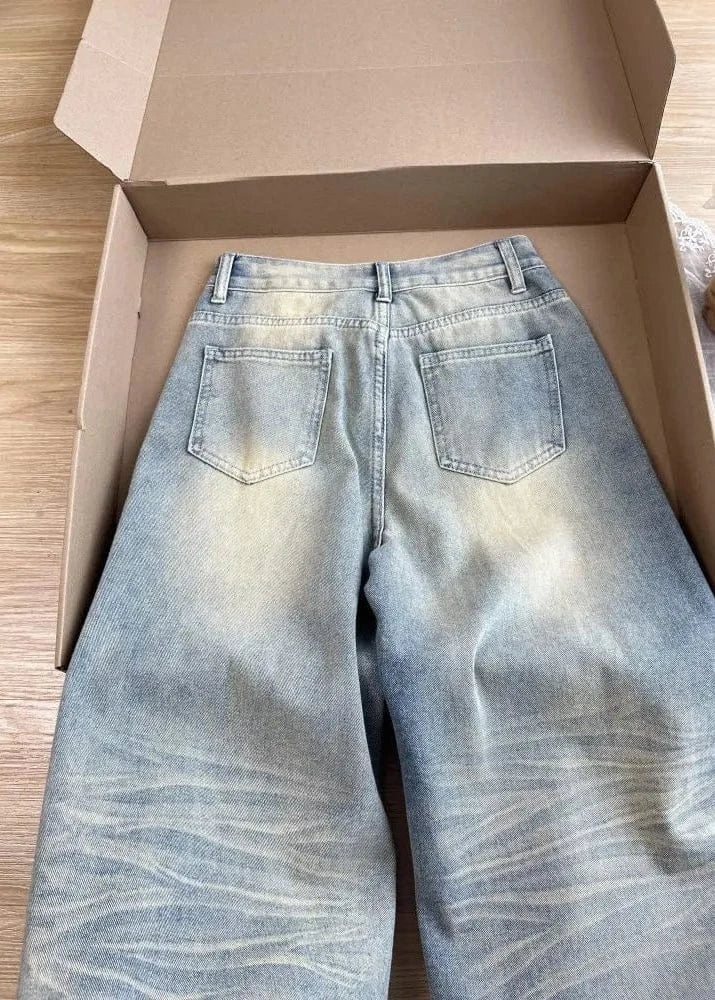 Light blue jeans inside an open cardboard box on a wooden surface.