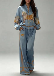 A woman models a light blue satin tracksuit featuring a horse and leopard print with gold trim, set against a neutral gray studio background.