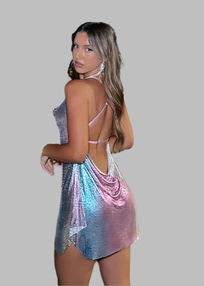 Woman in a colorful dress standing on a dock with city lights in the background