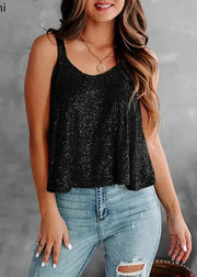 Woman wearing a black sequin tank top and blue jeans against a gray background