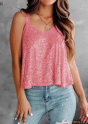 Woman wearing a pink sequin top and blue jeans against a gray background