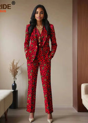 Woman wearing a red patterned suit standing in a room with beige walls and a couch.