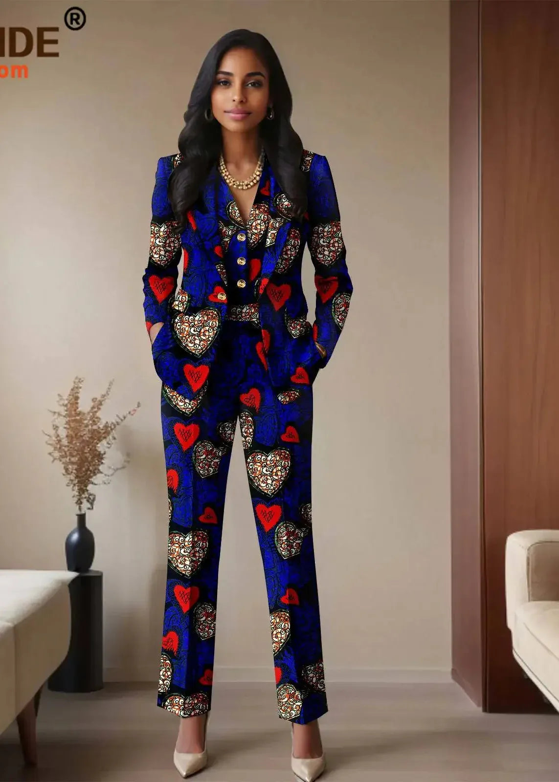 Woman wearing a colorful patterned suit in a room with beige walls and a couch.