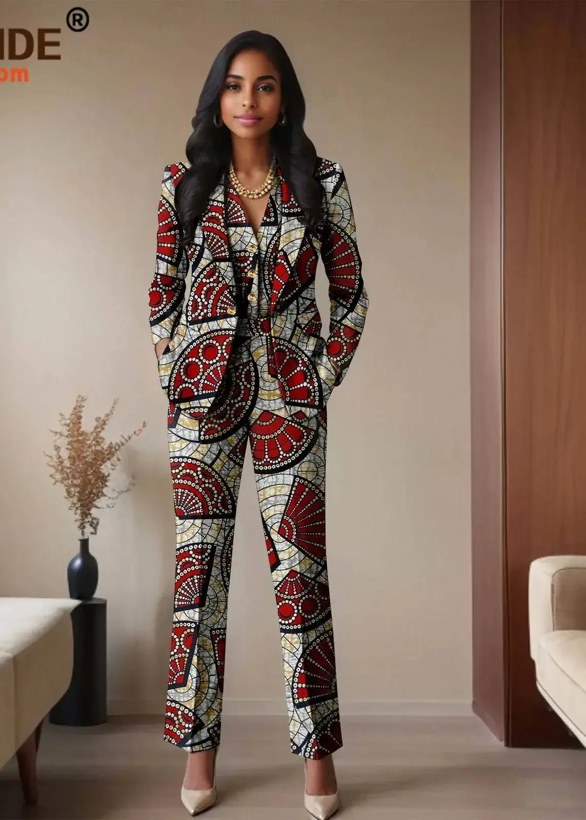 Woman wearing a patterned suit standing in a room with beige walls and a couch.