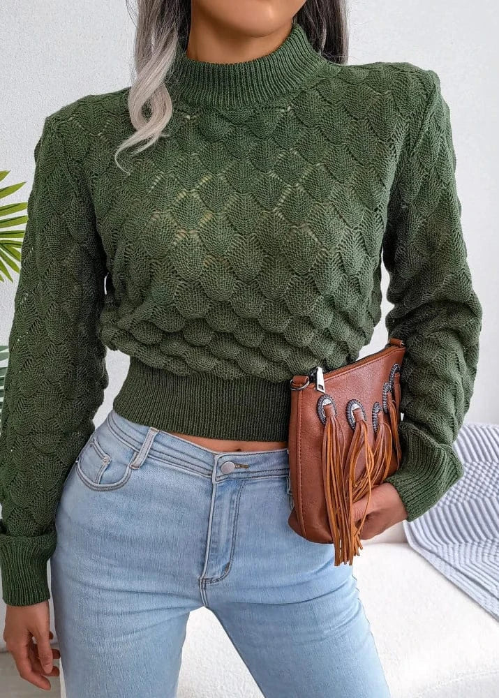 Person wearing a green knitted sweater and light blue jeans, holding a brown leather bag.