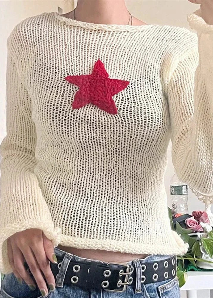 White knit sweater with a red star design worn by a person.