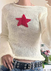 White knit sweater with a red star design worn by a person.