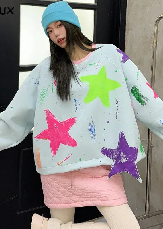Person wearing a colorful star-patterned sweater and pink skirt, holding a suitcase.