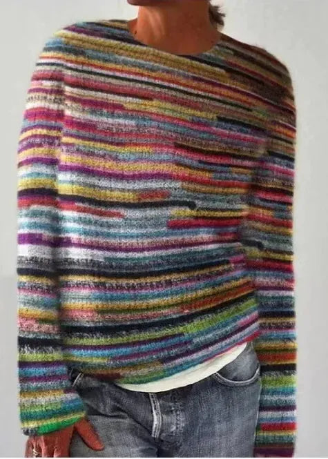 Person wearing a multicolored striped sweater against a plain background