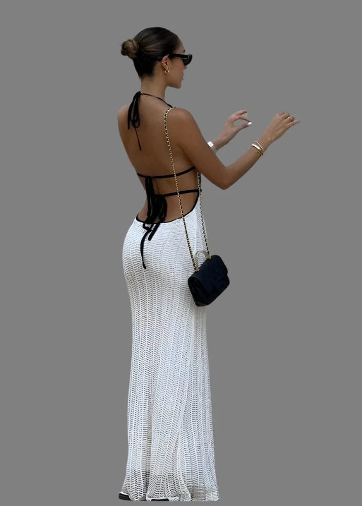 Woman in a white dress and black top interacting with a newspaper stand.