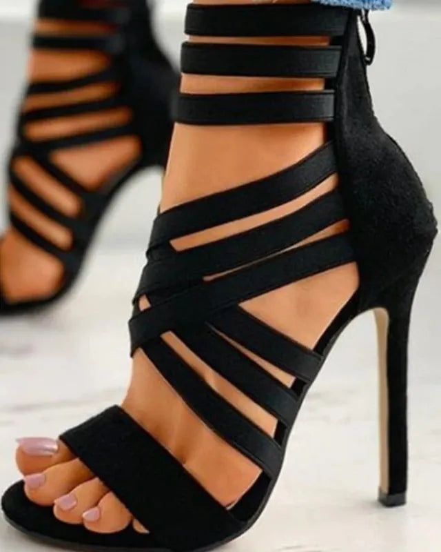 Black strappy high-heeled sandals on a light background