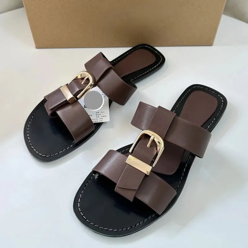 Pair of brown sandals with gold buckles on a white surface.