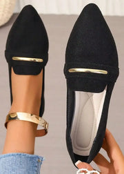 Black pointed-toe shoes with gold accents held by a person wearing gold bracelets.