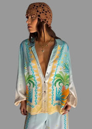 Woman wearing a patterned shirt and headscarf with a plain background