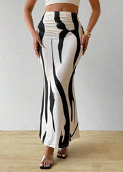 Person wearing black and white patterned pants against a plain background