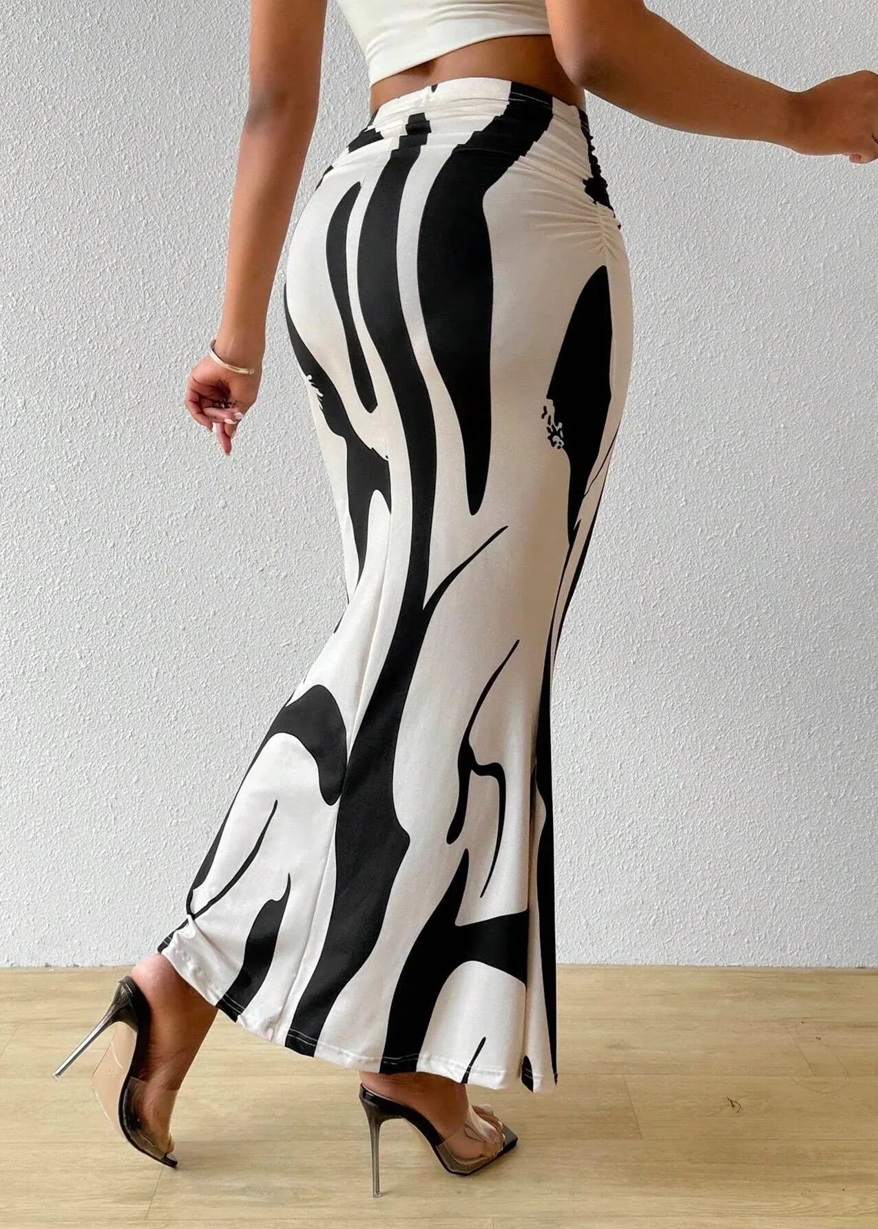 Person wearing a black and white patterned skirt on a plain background