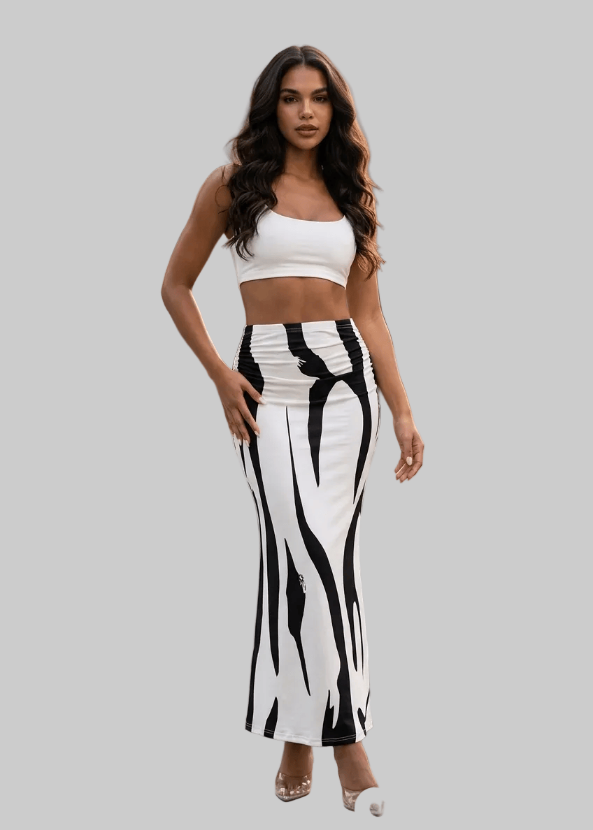 Woman in a white top and black and white striped pants standing on a city street.