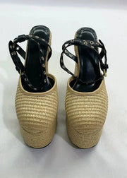 Pair of beige woven shoes with black straps on a white background
