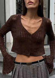 Woman wearing a brown knitted cardigan and gray skirt standing on steps.