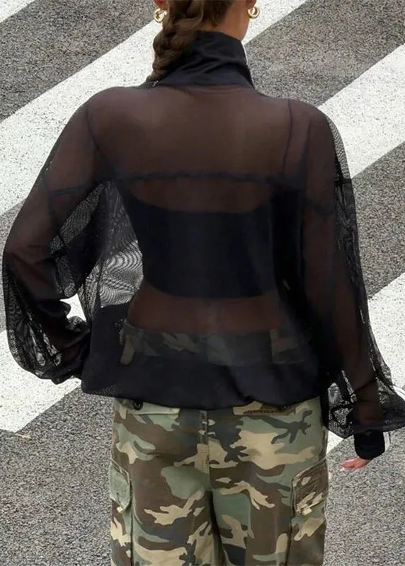 Person wearing a sheer black top and camouflage pants on a zebra crossing