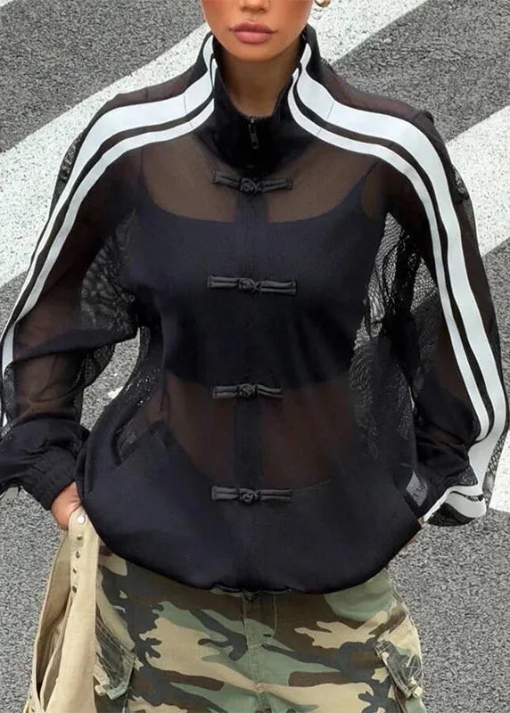 Person wearing a black outfit with sheer sleeves and camouflage pants on a crosswalk.