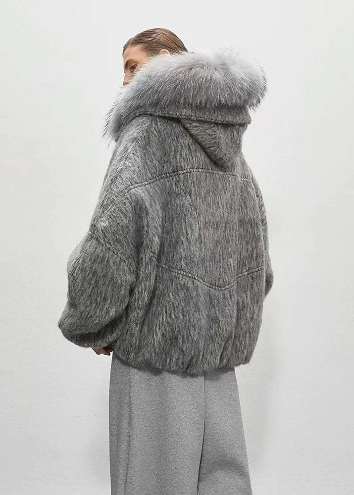 Person wearing a gray fur coat with a hood on a white background