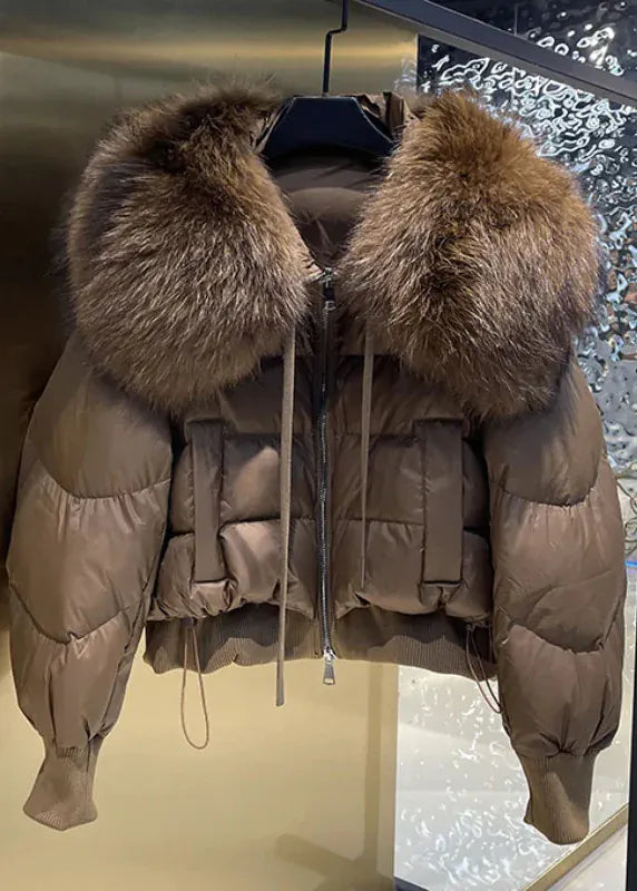 Beige puffer jacket with fur hood on a metallic surface