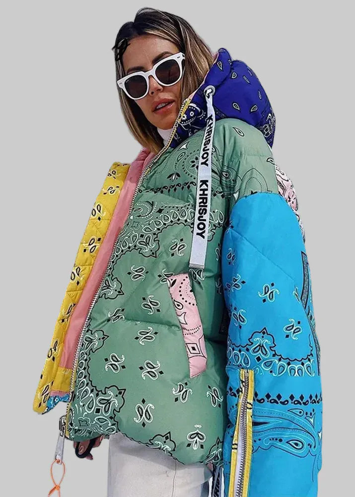 Person wearing a colorful patterned jacket with a blue hood in a snowy landscape.