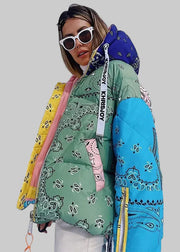 Person wearing a colorful patterned jacket with a blue hood in a snowy landscape.