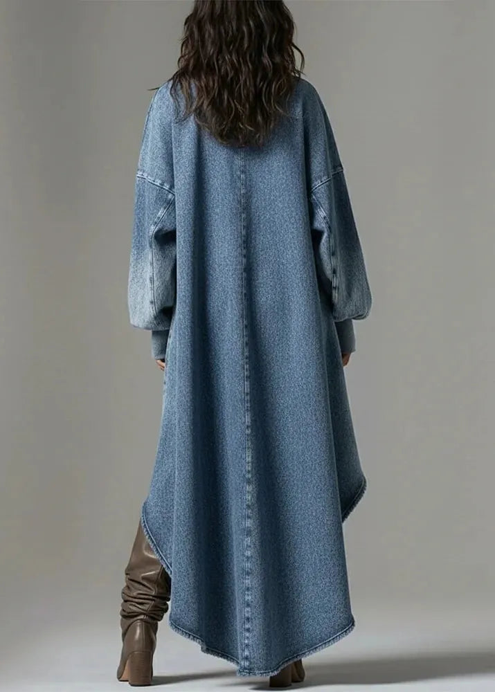 Person wearing a long denim coat with brown boots on a plain background