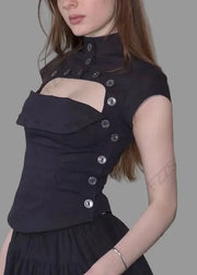 Woman wearing a black top with cut-out design against a white wall.