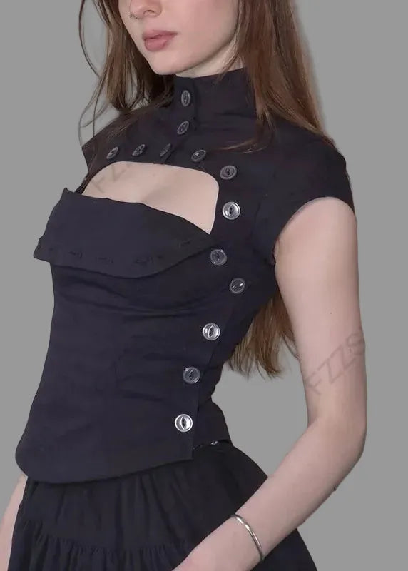 Woman wearing a black top with cut-out design against a white wall.