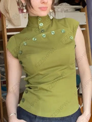 Person wearing a green sleeveless top with buttons, standing indoors.