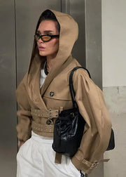 Person wearing a beige hooded jacket with a black backpack indoors.