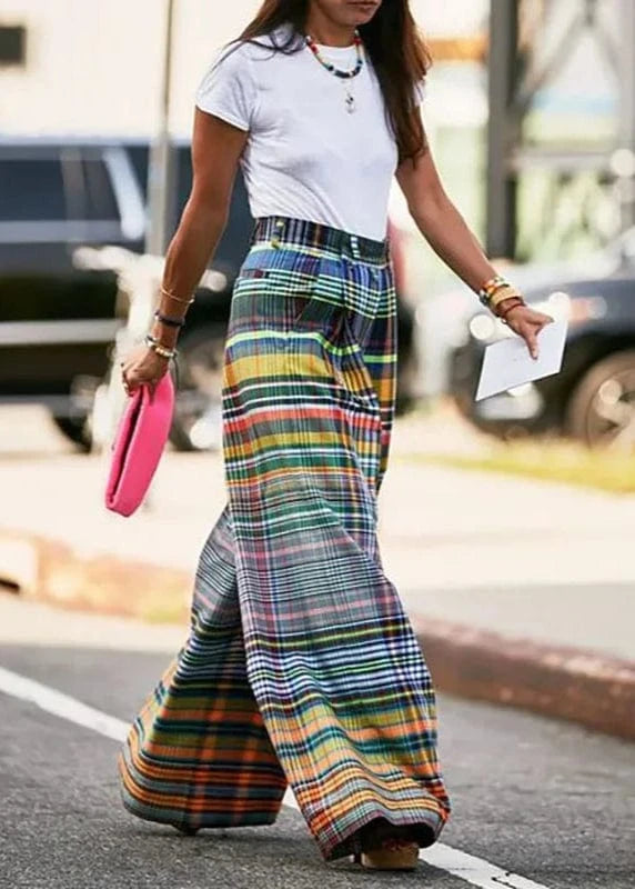 Person wearing colorful plaid pants and a white shirt on a street.