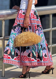 Person wearing a colorful patterned dress holding a straw bag by a metal railing.