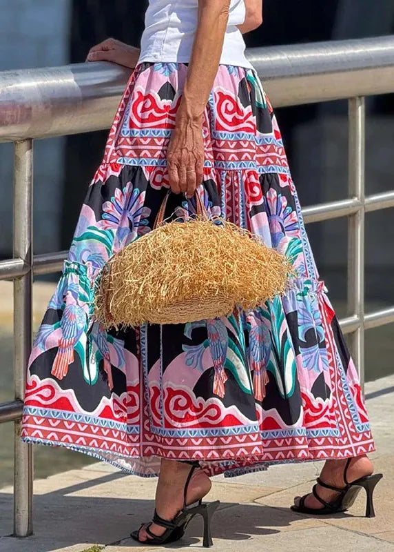 Person wearing a colorful patterned dress holding a straw bag by a metal railing.