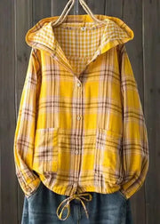 Yellow plaid shirt with a hood hanging against a wooden background
