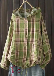 Green plaid shirt with a hood hanging against a wooden background