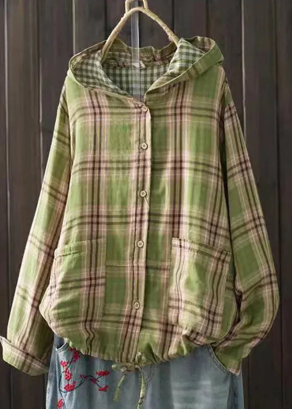 Green plaid shirt with a hood hanging against a wooden background